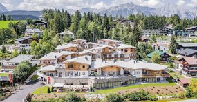 Das Alpina Seefeld in Tirol von AlpenParks. Die Appartementanlage füngt sich in die Sommerliche Alpenlandschaft ein.