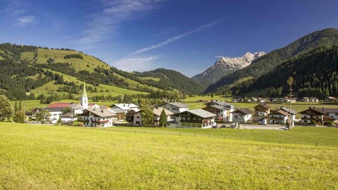 Der Ort Mittersill aus der Ferne mit inmitten grün gelber Wiesen und Hügel
