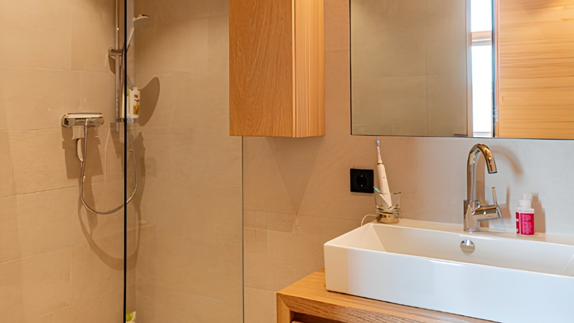 Badezimmer im Ferienchalet mit ebenerdiger Dusche, Holzmöbeln und Waschbecken, Egg