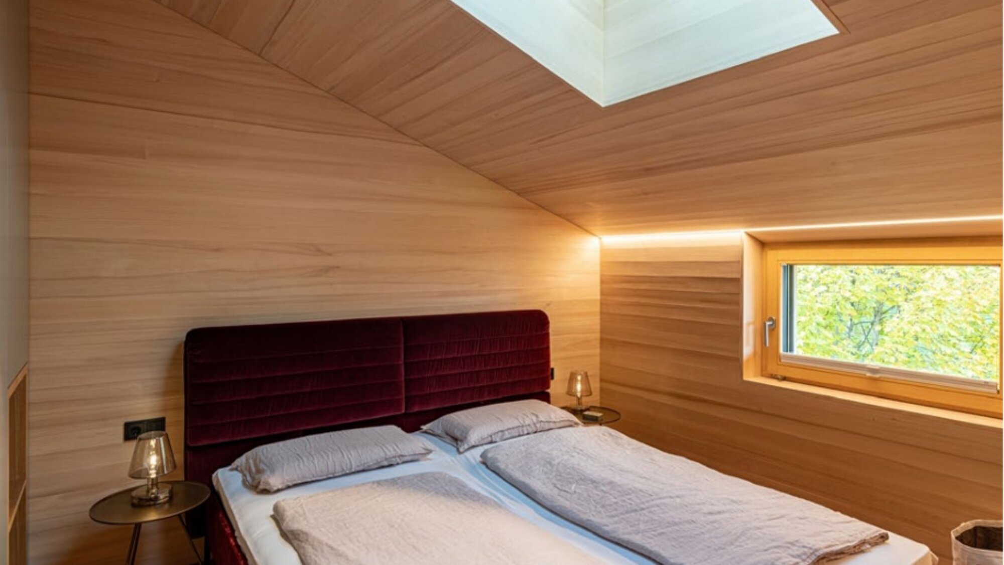 Schlafzimmer im Ferienchalet mit Doppelbett, Holzwänden und Dachfenster in Egg, Vorarlberg