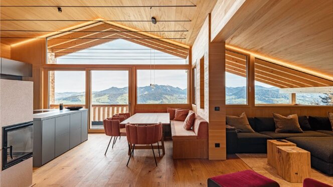 Wohn- und Essbereich mit Kamin, Sitzbank und großem Bergblickfenster im Ferienchalet, Egg