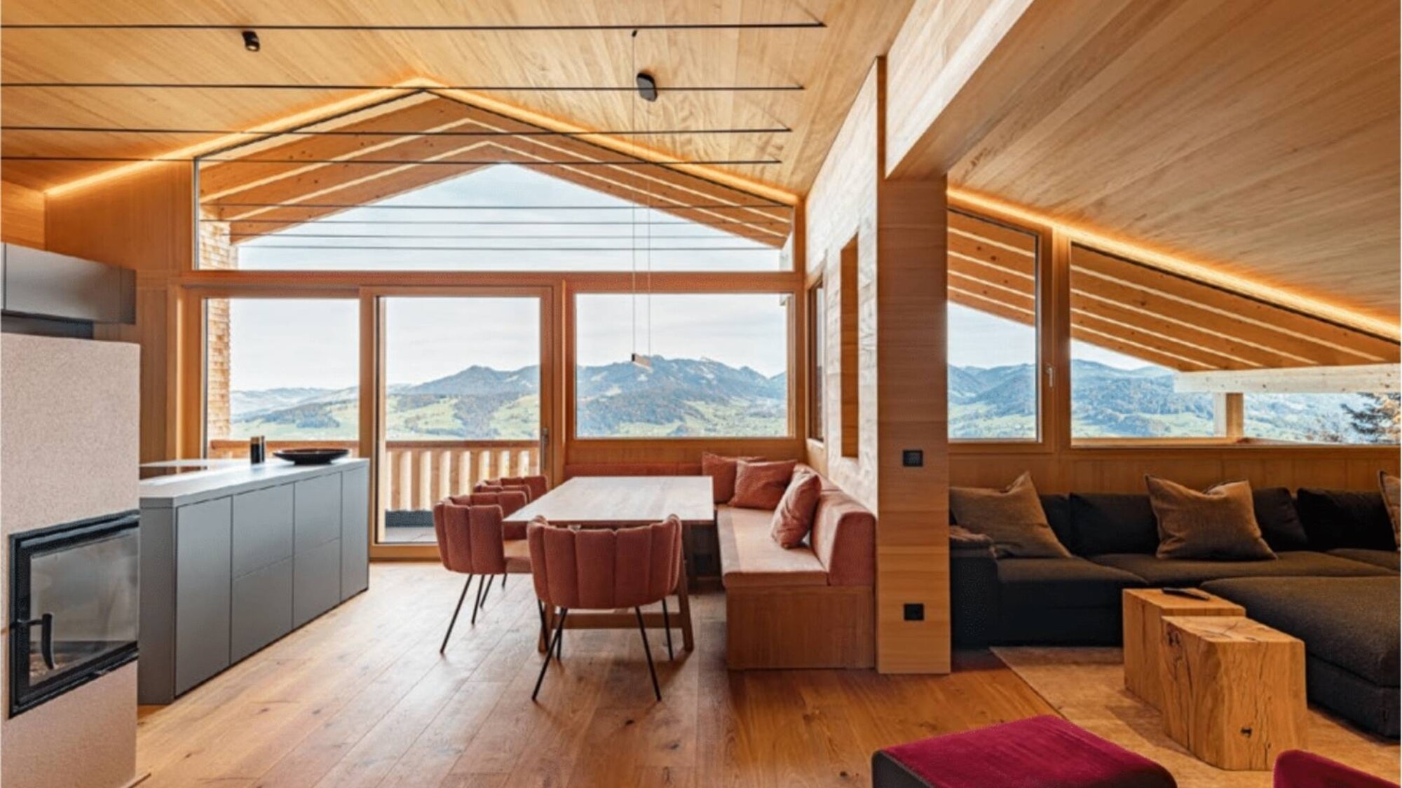 Wohn- und Essbereich mit Kamin, Sitzbank und großem Bergblickfenster im Ferienchalet, Egg