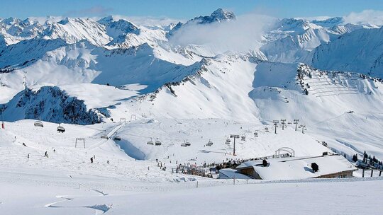 Verschneite Skipiste mit Liften und Bergpanorama im Winter in Vorarlberg, Österreich