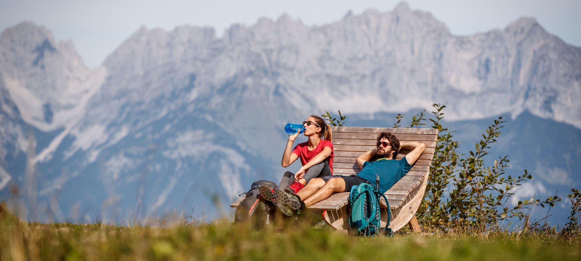 Wanderer auf einer Bank vor Alpenkulisse